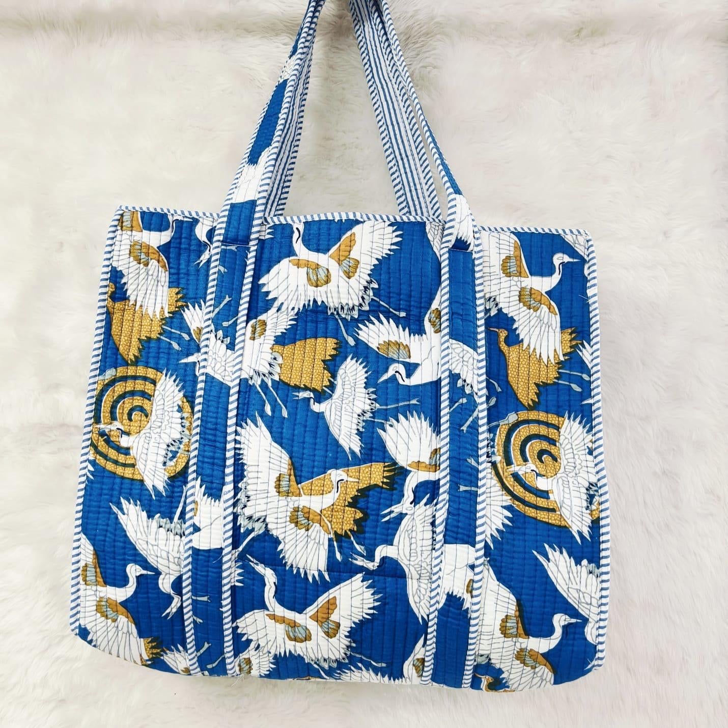 Blue tote bag with bird pattern on a light gray background