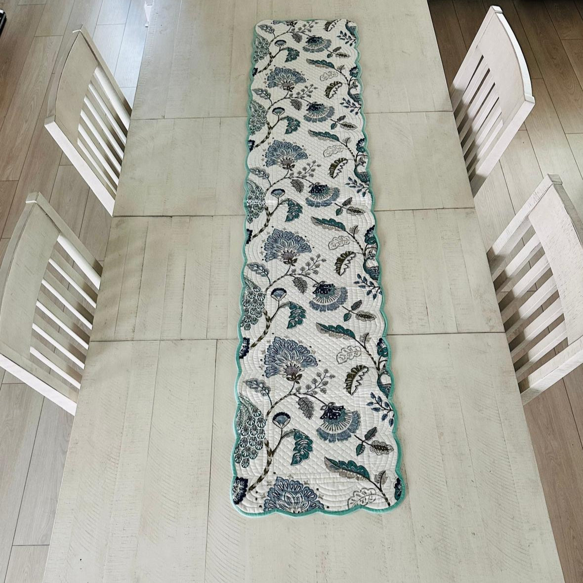 Floral patterned table runner on a wooden dining table with chairs.
