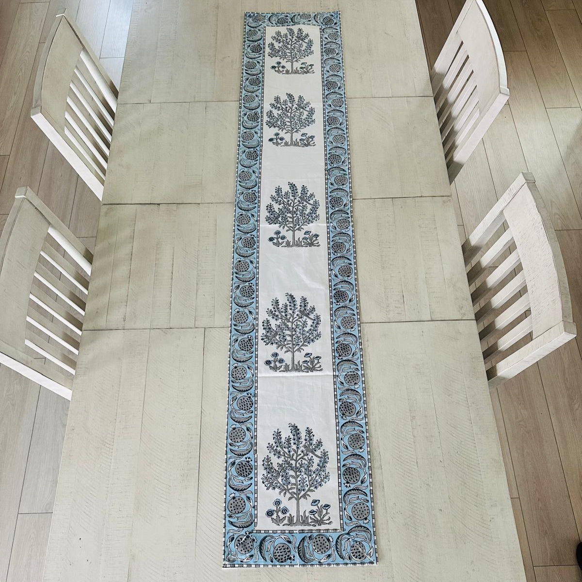 Decorative table runner with tree pattern on a light wooden table