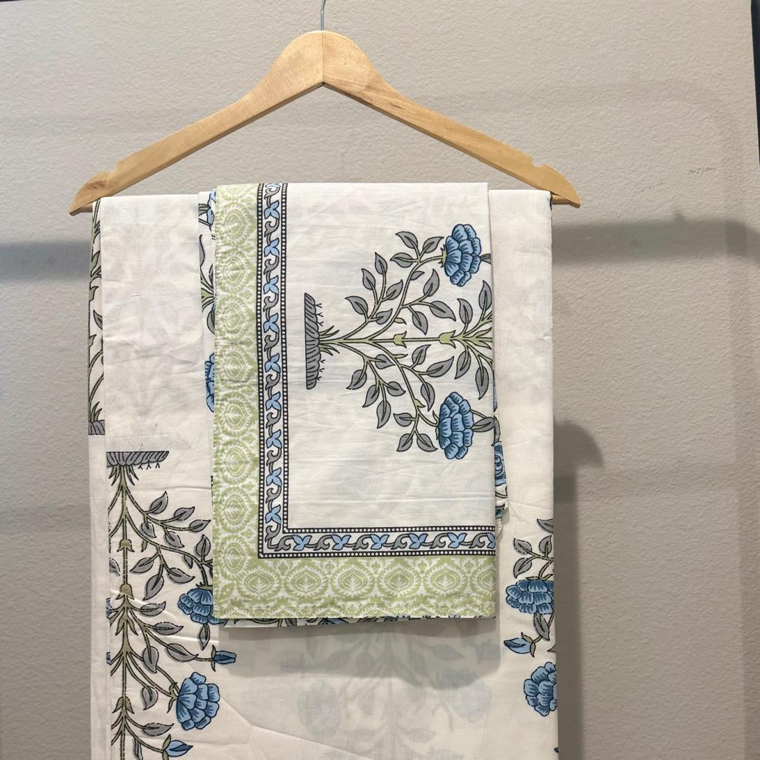 Set of patterned towels hanging on a wooden hanger against a neutral background