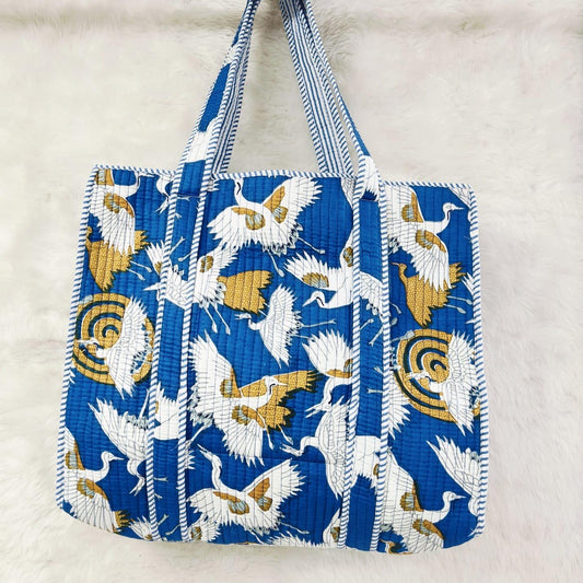 Blue tote bag with bird pattern on a light gray background