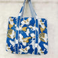 Blue tote bag with bird pattern on a light gray background