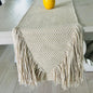 Beige woven table runner with fringe on a wooden table