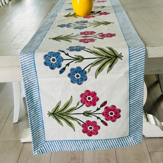 Embroidered floral table runner on a dining table with a yellow vase.