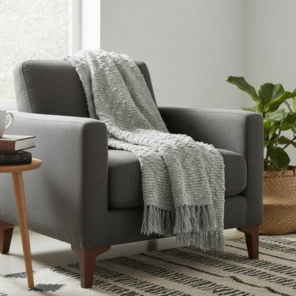 Gray armchair with a blanket in a cozy living room setting