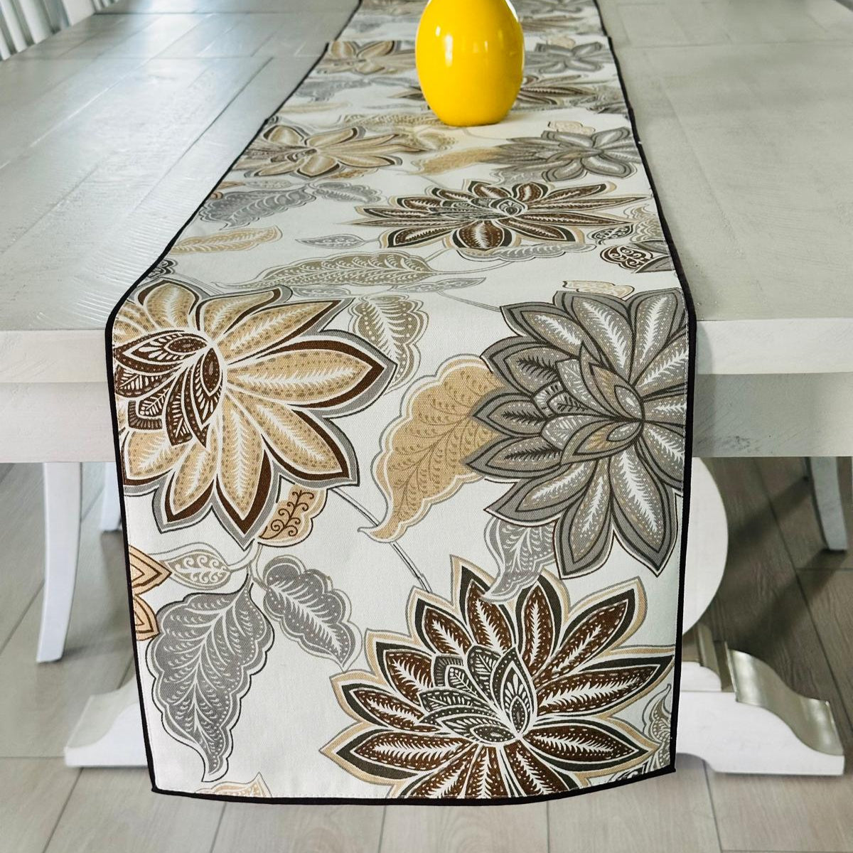 Floral patterned table runner on a dining table with a yellow vase.