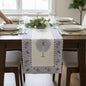Dining table set with a decorative table runner, glasses, and plates.