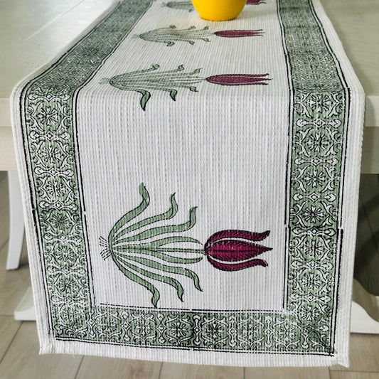 Decorative table runner with crocodile and lily design on a wooden table.