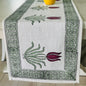 Decorative table runner with crocodile and lily design on a wooden table.