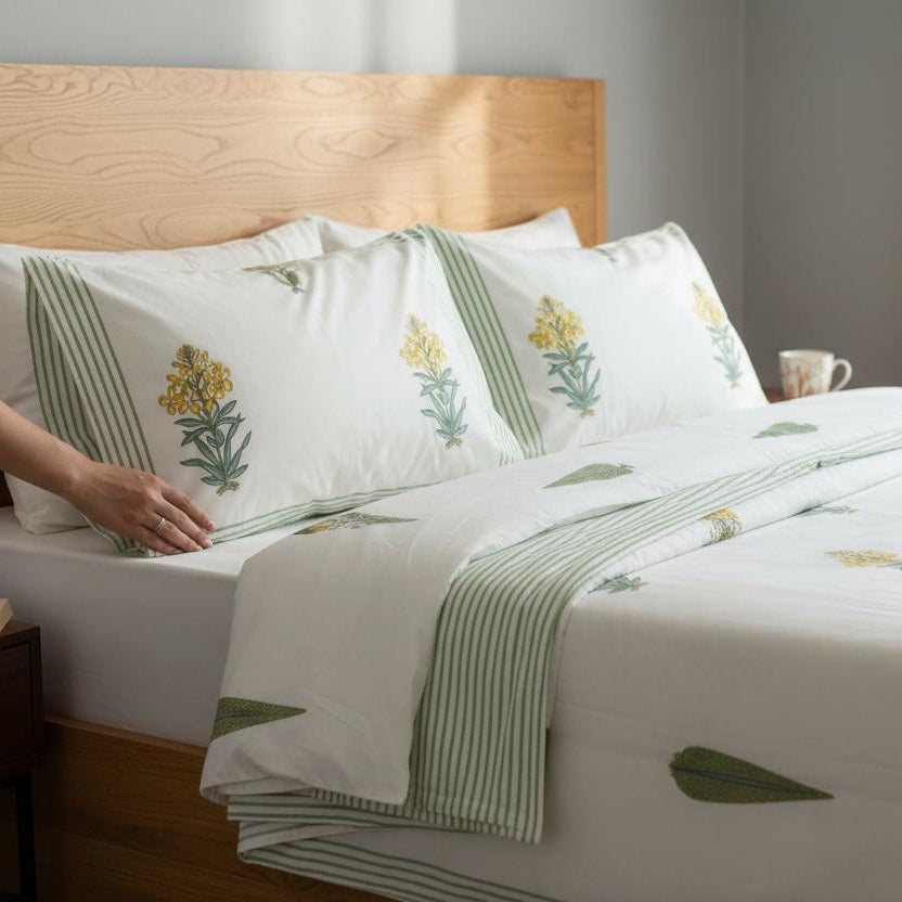 Bed with floral-patterned bedding and a person reading a book.