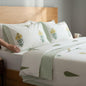 Bed with floral-patterned bedding and a person reading a book.