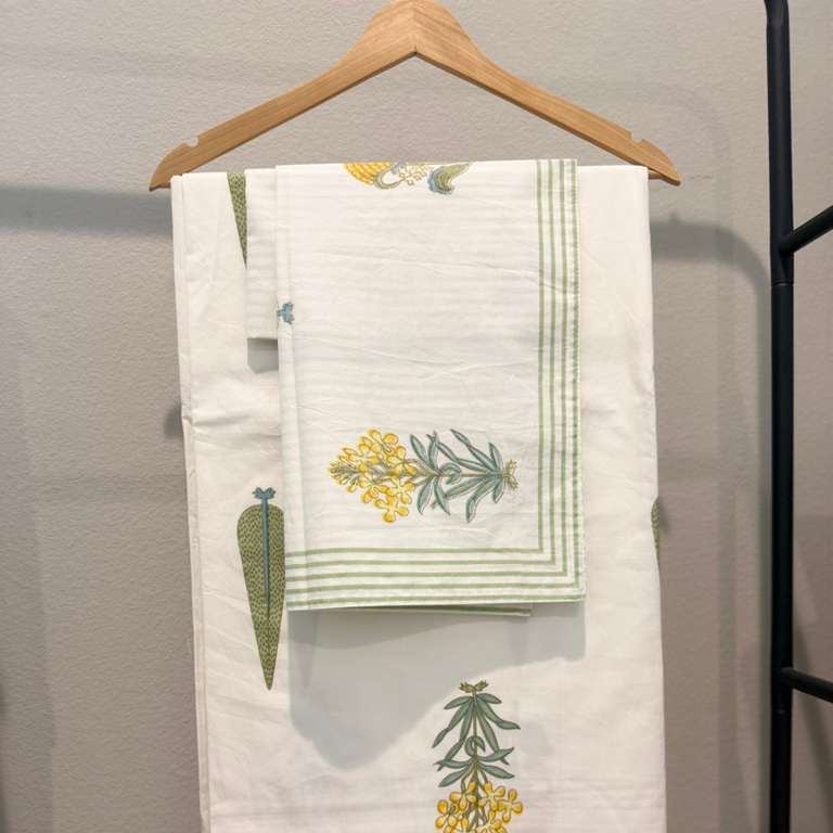 Set of towels with floral embroidery on a wooden hanger against a gray wall.