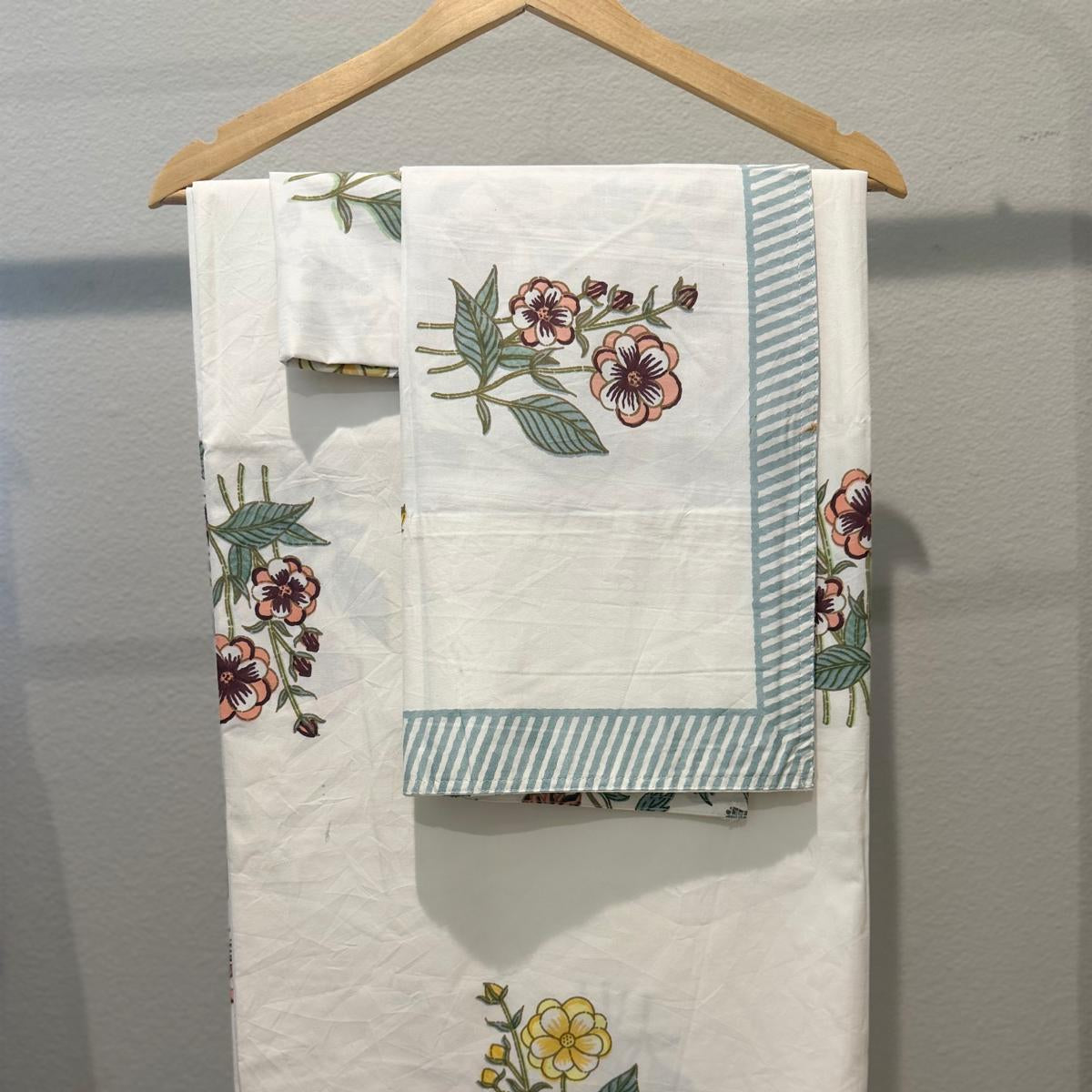Set of embroidered towels with floral designs on a wooden hanger against a gray background