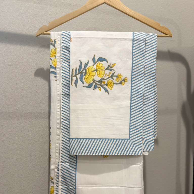 Towel with floral design and blue stripes hanging on a wooden hanger against a gray wall.