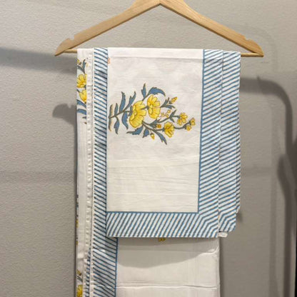 Towel with floral design and blue stripes hanging on a wooden hanger against a gray wall.