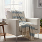 White armchair with a blue and beige plaid blanket in a bright living room.